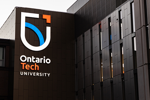 View of exterior campus building with brightly lit Ontario Tech University logo