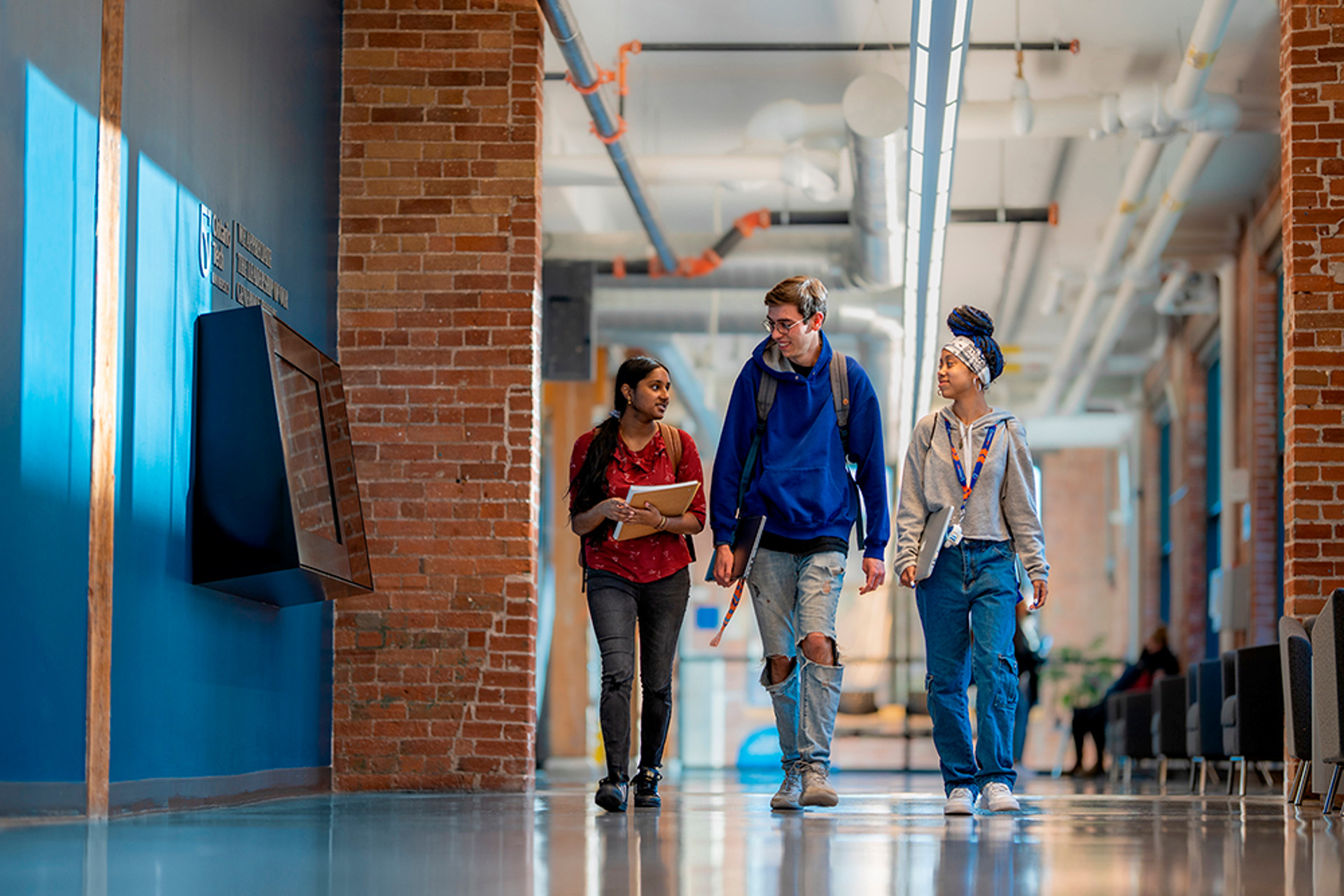 Three students walking down a hallway talking to one another